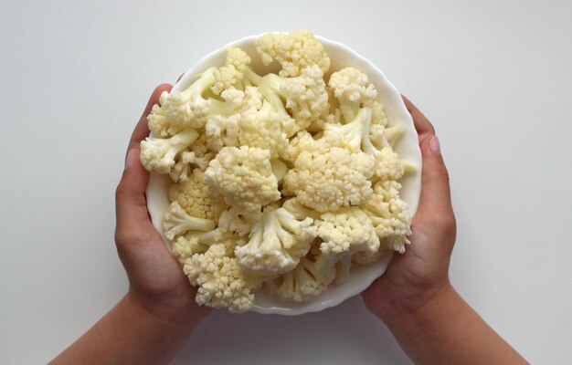 Cauliflower divided into inflorescences in a cup in childrens hands