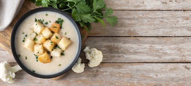 Cauliflower soup in a bowl on wooden table