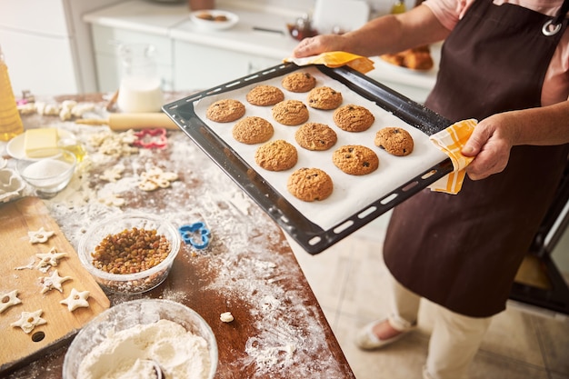 Cautious lady carrying a tray with hot cookies to table