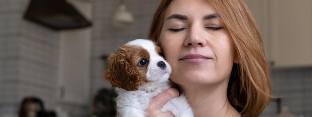 Cavalier King Charles Spaniel Blenheim Banner Close up portrait of Cute dog puppy with woman hostess