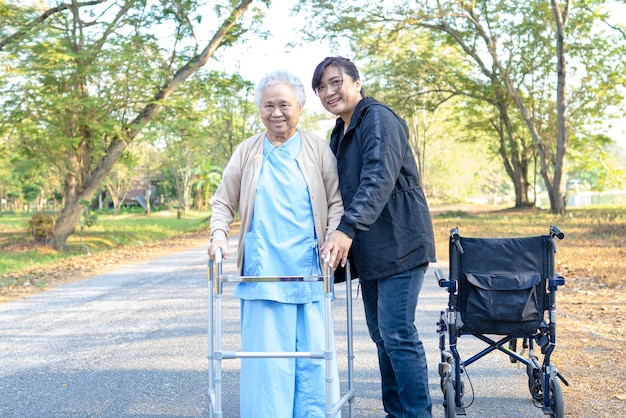 Cavergiver help and care Asian senior or elderly old lady woman with strong health while walking at park in happy fresh holiday