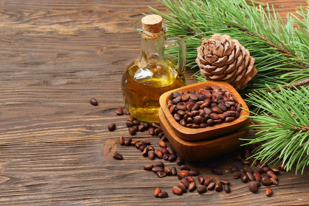 Cedar cones, nuts and cedar nut oil in a transparent bottle on a wooden table