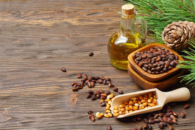 Cedar cones, nuts and cedar nut oil in a transparent bottle on a wooden table