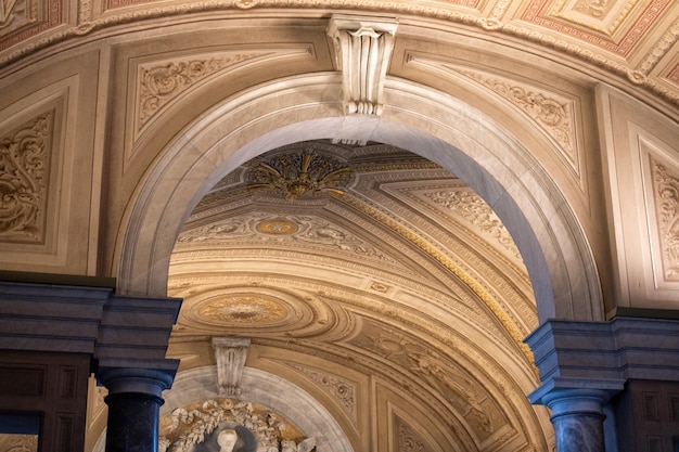 The ceiling of a building is decorated with a lot of gold and white designs