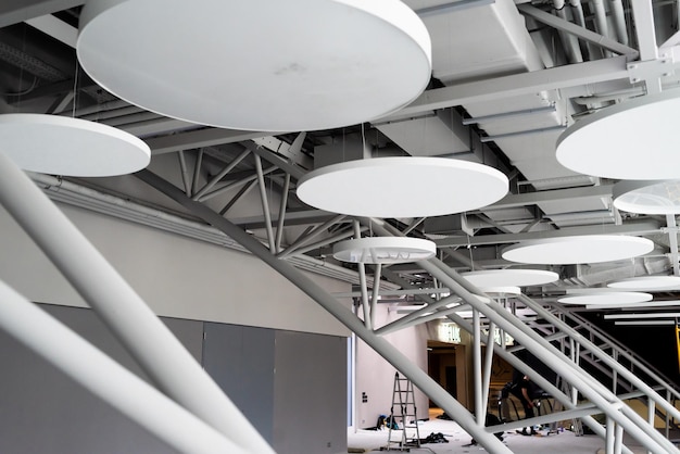 A ceiling with white plates and a man working on a project.