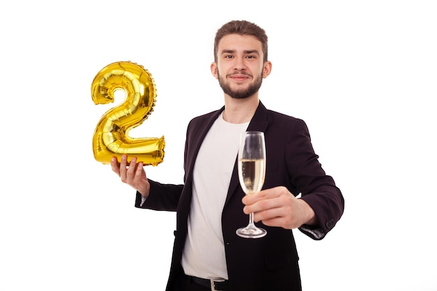 Celebrating a Caucasian bearded man holding a yellow bouncy figure two and a glass of champagne