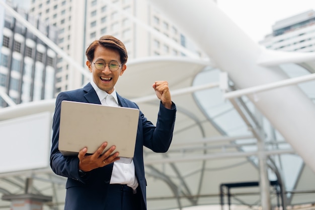 Celebrating success arms raised. Cheerful Asian business man celebrating success outdoors