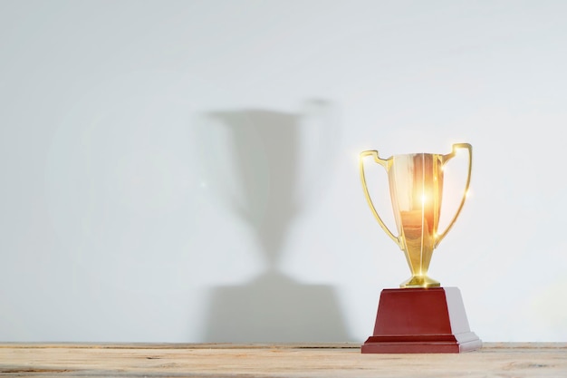 Celebrating the success that has happened Gold trophy placed at work desk There is a large reflection of the trophy Free space to put text into advertising media