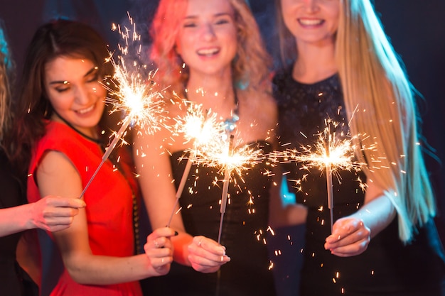 Celebrating with fun. Group of cheerful young women carrying sparklers. New year, holidays and party concept.