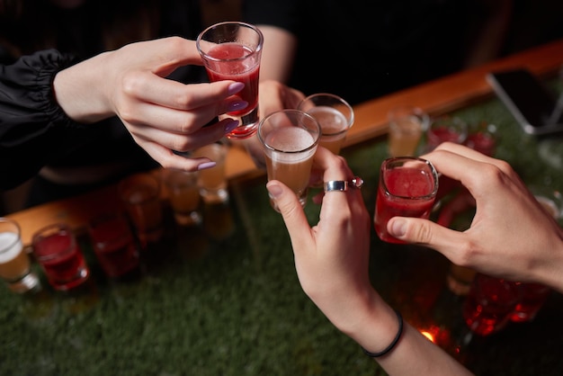 Celebrating with glasses of alcohol in hands happy female friends having good time