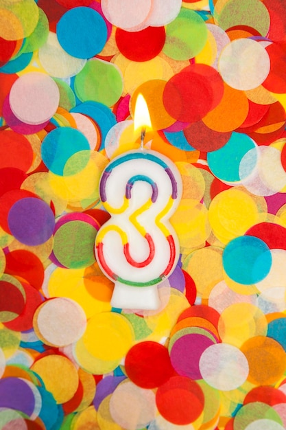 Celebration candle number 3 on a confetti background