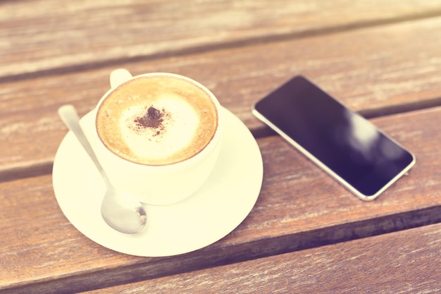 Cell phone and cup of coffee on the table