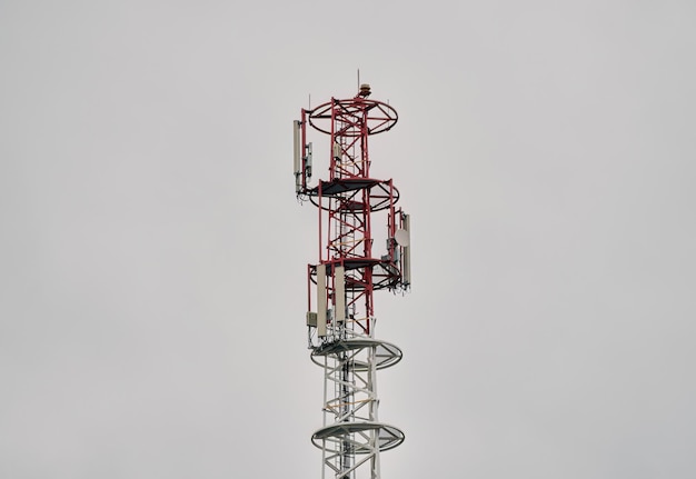 A cell phone tower with a dark sky behind it