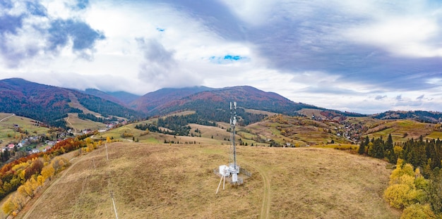 Cell tower near mountain settlement under gloomy sky