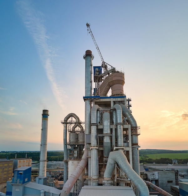 Cement plant with high factory structure and tower cranes at industrial production area Manufacture and global industry concept