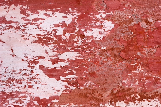 cement wall with red paint, rough background. Abstract concrete background with old peeling red paint.