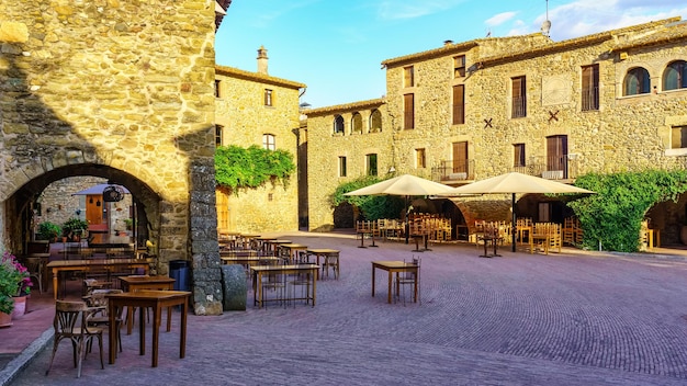 Central Square of the medieval village of Monells with its stone houses and arches in the buildings Girona Spain