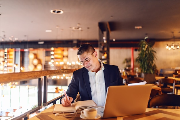 CEO writing in agenda schedule in cafe.