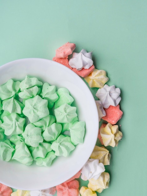 Ceramic bowl full of colorful merengues at pastel mint background