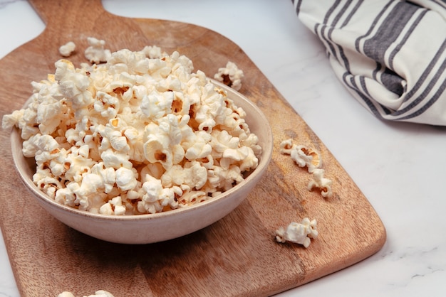 Ceramic bowl on a rustic wooden board with popcorn