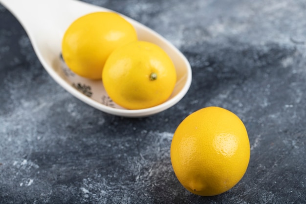 Ceramic bowl of three juicy ripe lemons placed marble surface