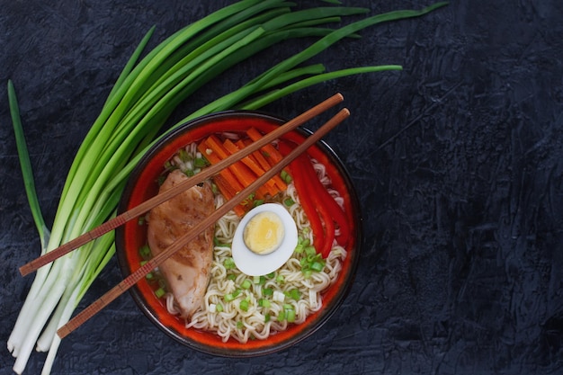 Ceramic bowl of traditional asian ramen soup with noodles spring onion chicken and sliced egg