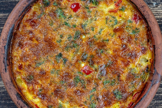 Ceramic bowl with vegetable frittata simple vegetarian food Frittata with tomato pepper onion and cheese on wooden table close up Italian egg omelette