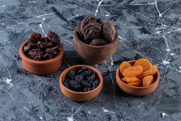 Ceramic bowls of tasty dried fruits on marble surface. 