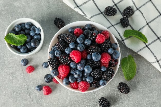 Ceramic bowls with berries on grey space, top view