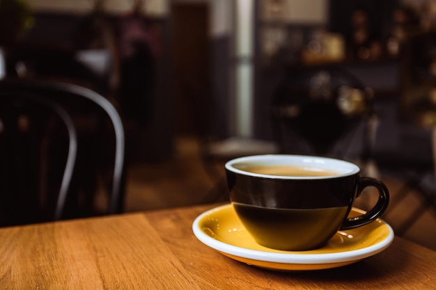 A ceramic cup of black coffee on the wooden table in a cafe