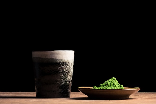 a ceramic cup and green tea powder on the table