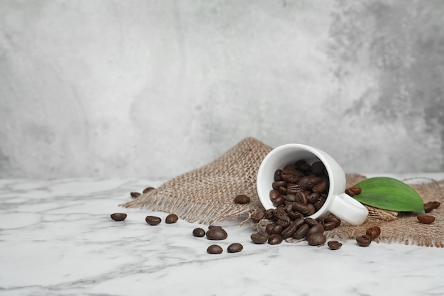 Ceramic cup with coffee beans on marble table