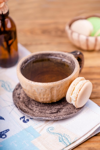 Ceramic cup with tea and macaron on a wooden table copy space