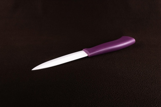 Ceramic kitchen knife wi on dark brown background