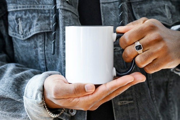 Ceramic mug mockup close up africanamerican in a denim jacket holding white cup with black handle of