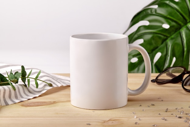 Ceramic mug on wooden desktop next to striped tablecloth