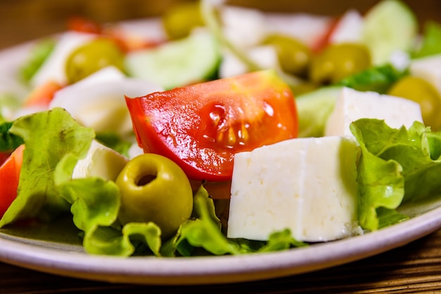 Ceramic plate with greek salad on wooden table