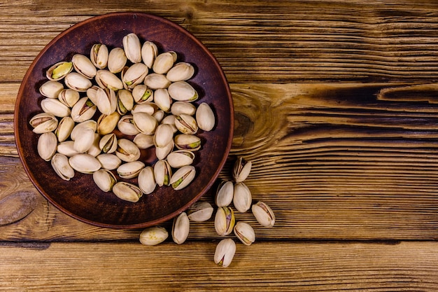 Ceramic plate with pistachio nuts on a wooden table Top view