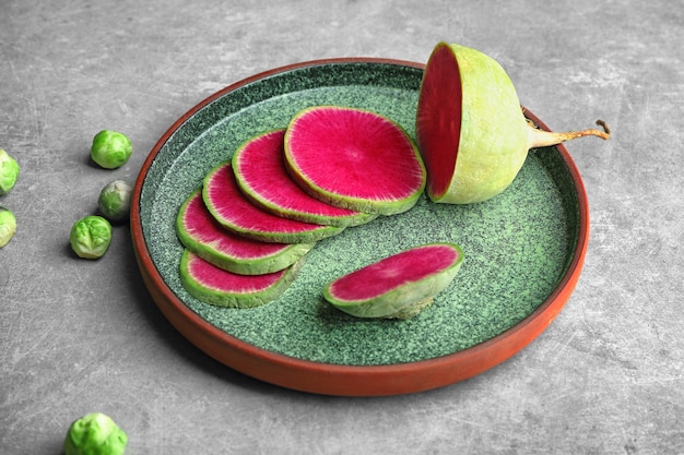 Ceramic plate with radish on grey background