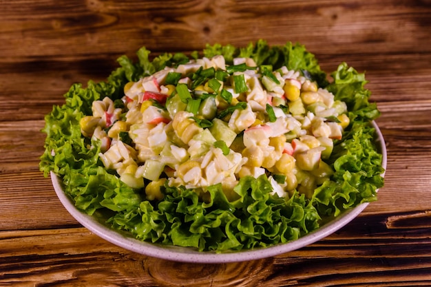 Ceramic plate with salad from crab sticks on wooden table