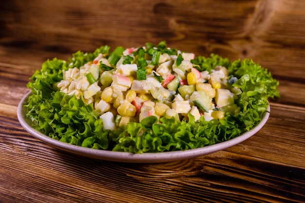 Ceramic plate with salad from crab sticks on wooden table