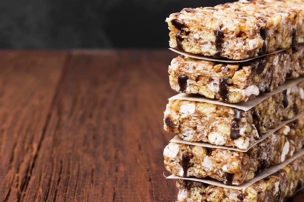 Cereal bars with nuts, berries and cinnamon on a wooden background.