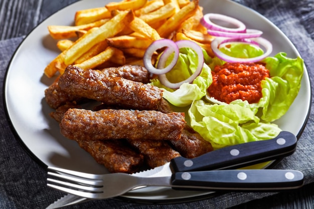 Cevapcici with potato fries lettuce onion ajvar