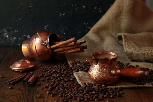 Cezve-traditional cup of coffee, bag and scoop on old rusty background. Dark food photography.