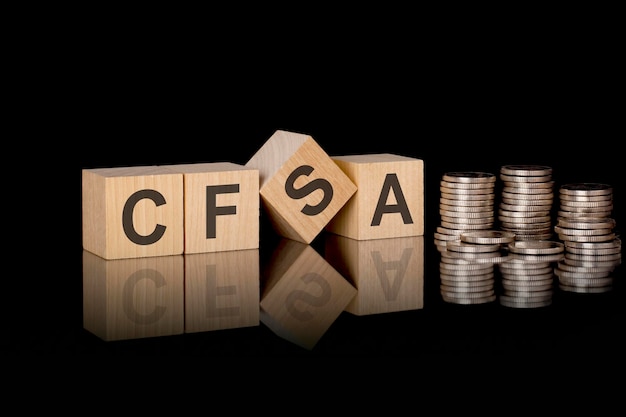 Cfsa text on wooden cubes on dark backround with coins business concept