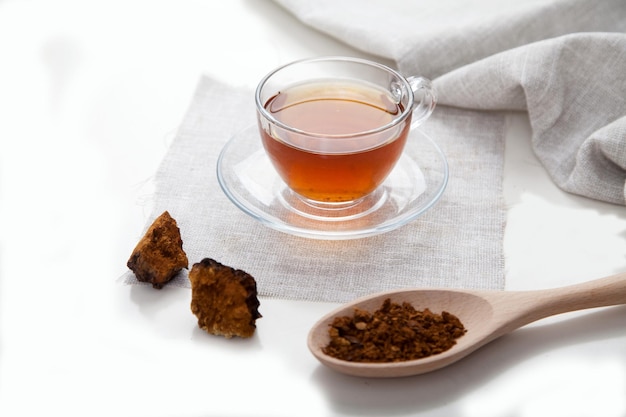 Chaga coffee in a glass cup pieces of chaga and a linen salyette on a light background Health concept