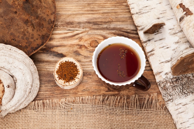 Chaga tea in a cup on wooden table. Rustic style.