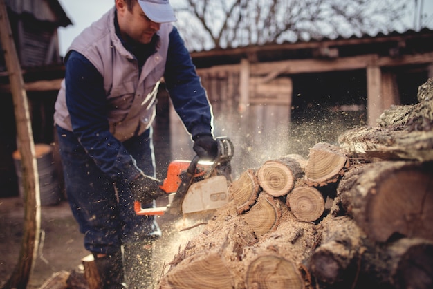 Photo chainsaw in action cutting wood. man cutting wood with saw, dust and movements.