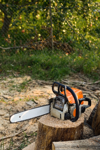  Chainsaw that stands on a heap of firewood in the yard on green grass 