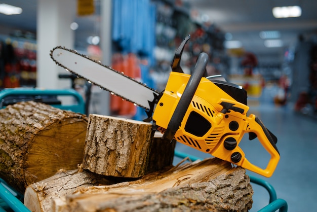 Chainsaw and wooden stump on showcase in power tool store closeup, nobody. Choice of equipment in hardware shop, electrical instrument in supermarket